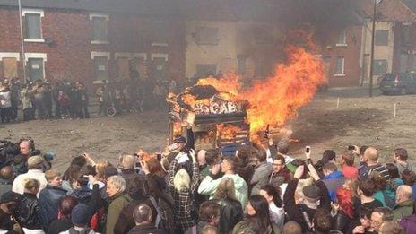 People standing around a burning effigy of Margaret Thatcher in a coffin.