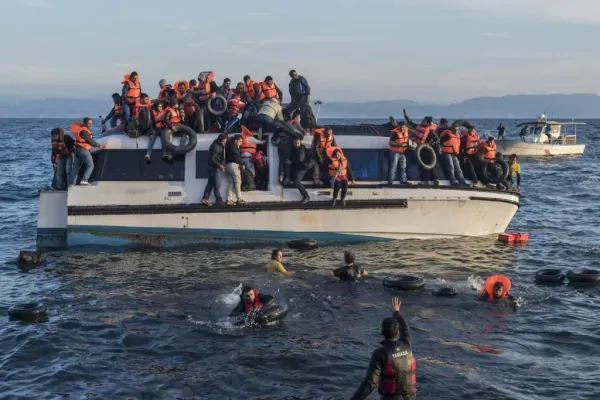 Refugees on a boat, many in the sea around it 